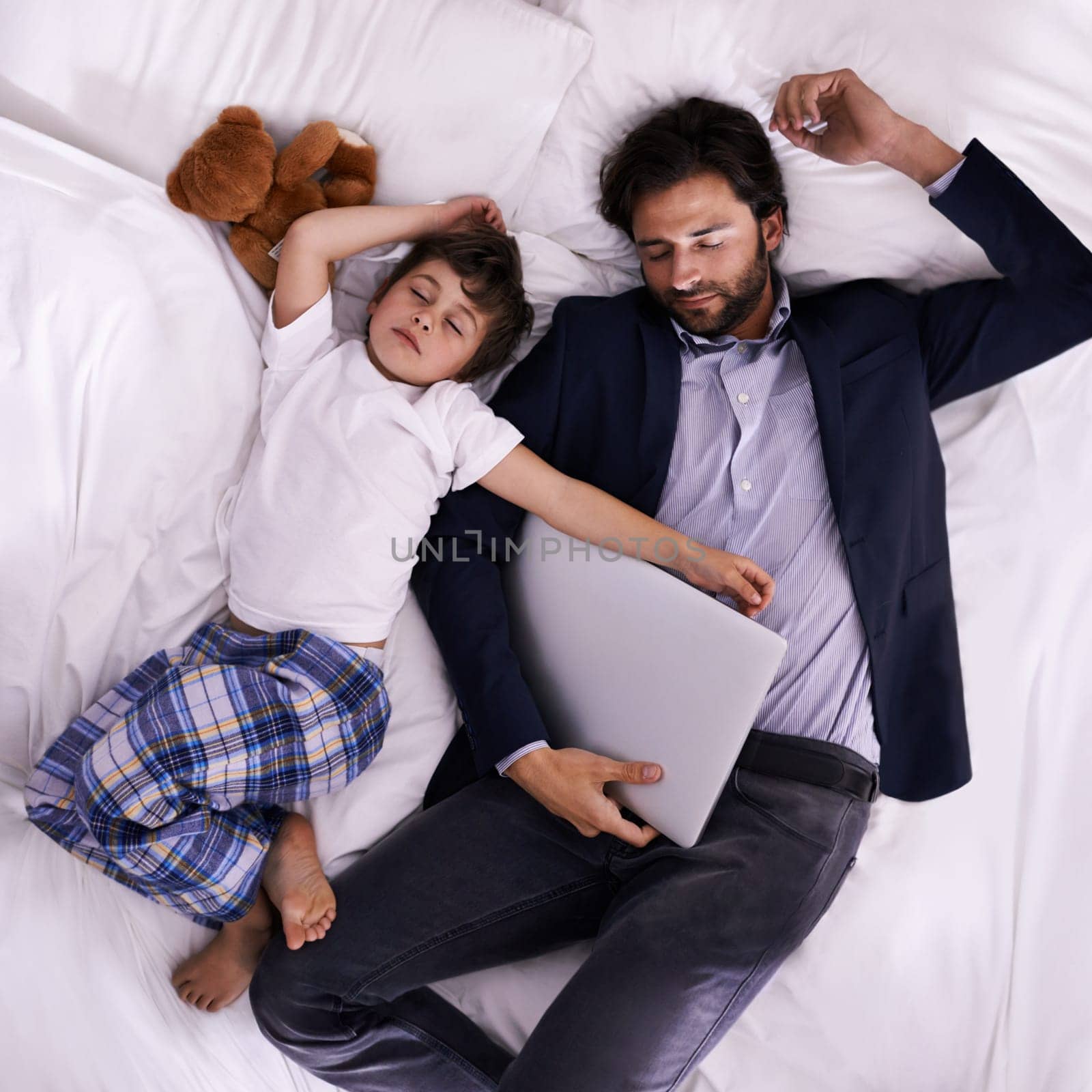 Tired, businessman and sleep with son, laptop for rest with technology and suit. Father, child and bedroom with fatigue, love and above with freelance peace or remote work for stress management.