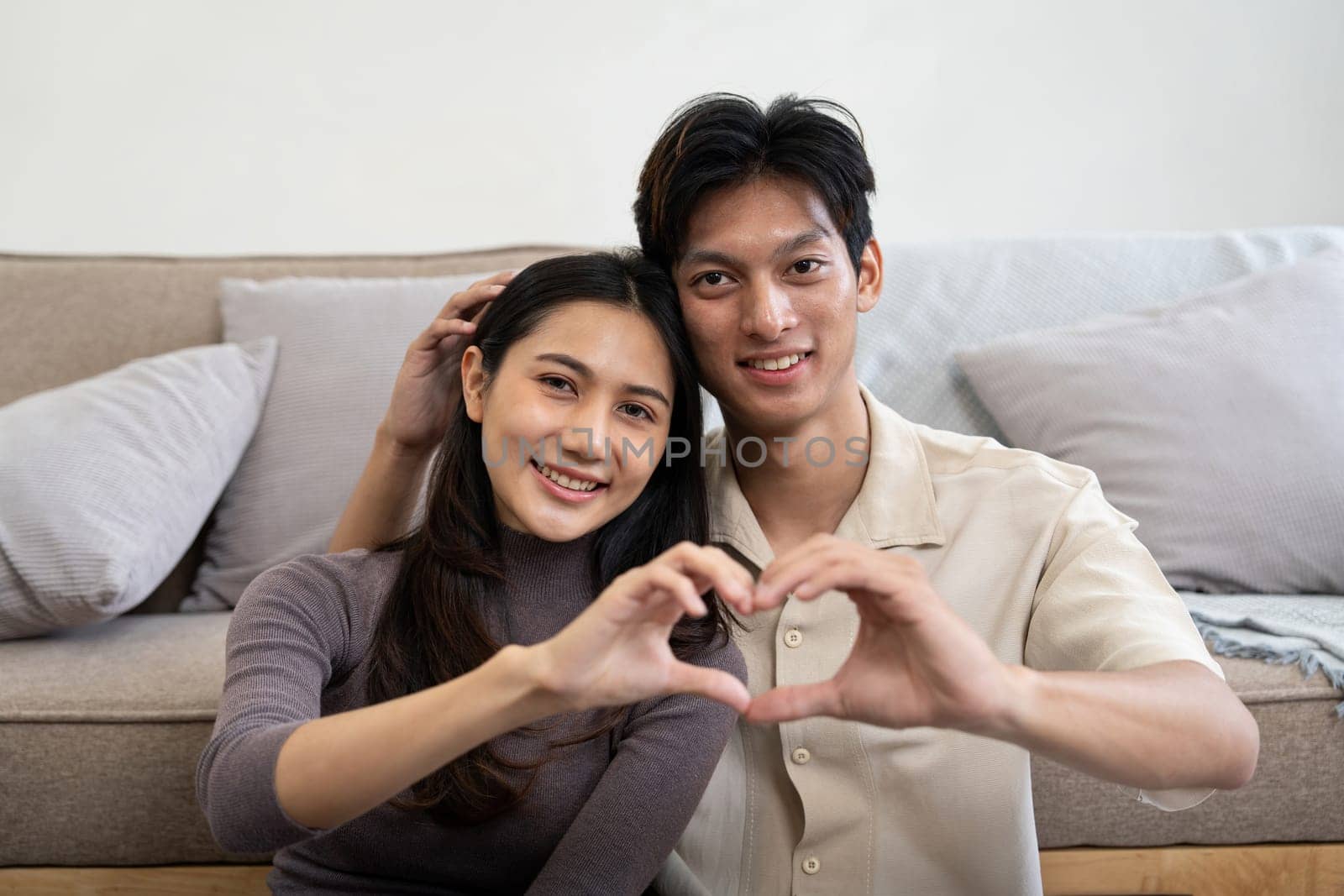 Lovely young couple asian is making heart sign with hands at home. Valentine day celebration.
