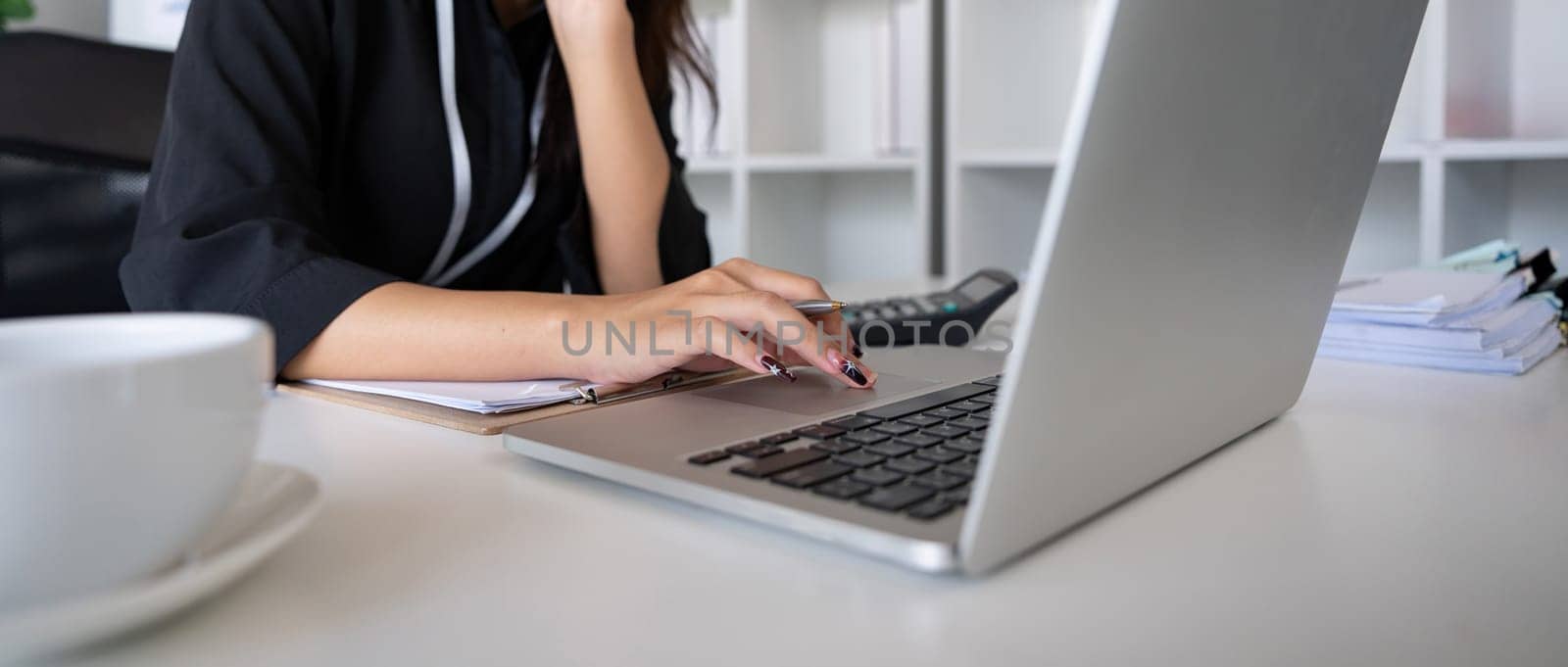 Businesswoman working using laptop computer to record and print information for a marketing plan analyze the balance sheet report financial statement.