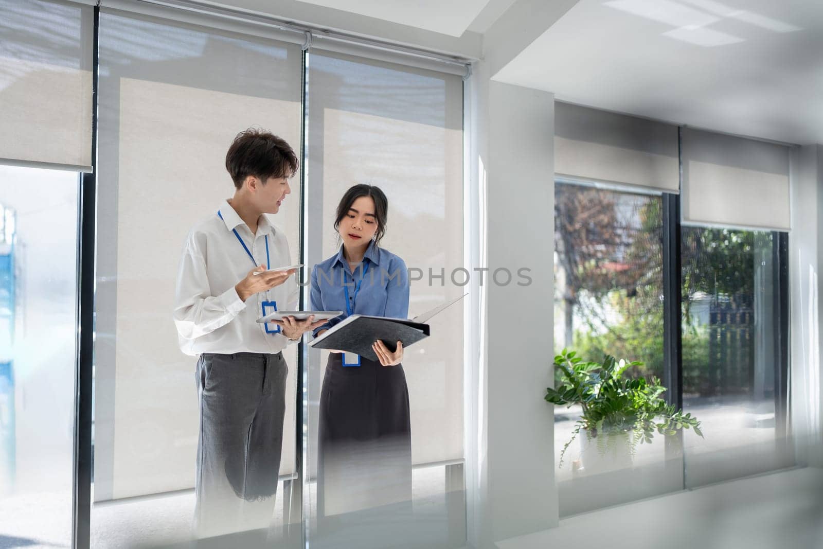 Two business asian people smiling as they go through a document together in an office by nateemee