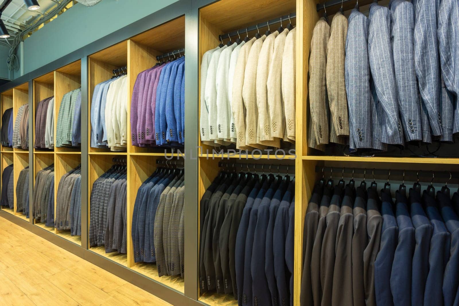A row of men's suits, jackets hanging on a rack for display. Elegant man suit jackets hanging in a row on hangers.