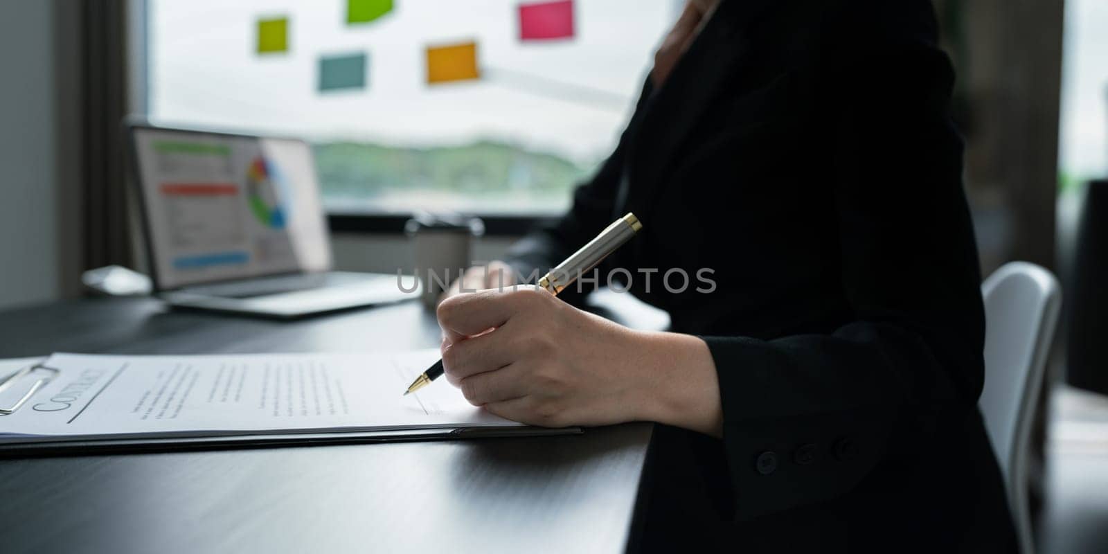 Close up image of businessman hand putting signature on contract document in presence of business partner by itchaznong