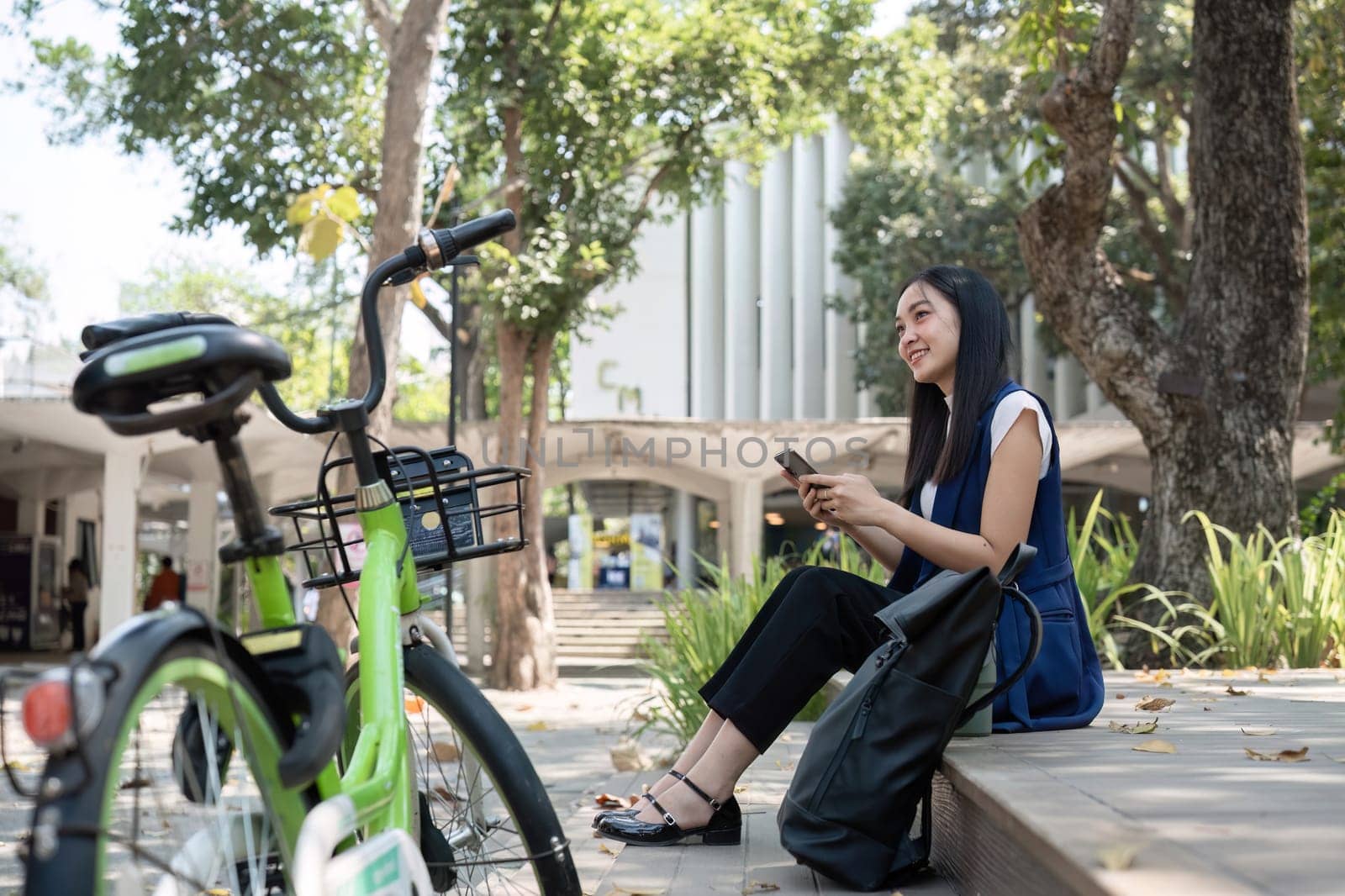 Asian business woman sitting and working in a nature park Travel by bicycle to save the environment.