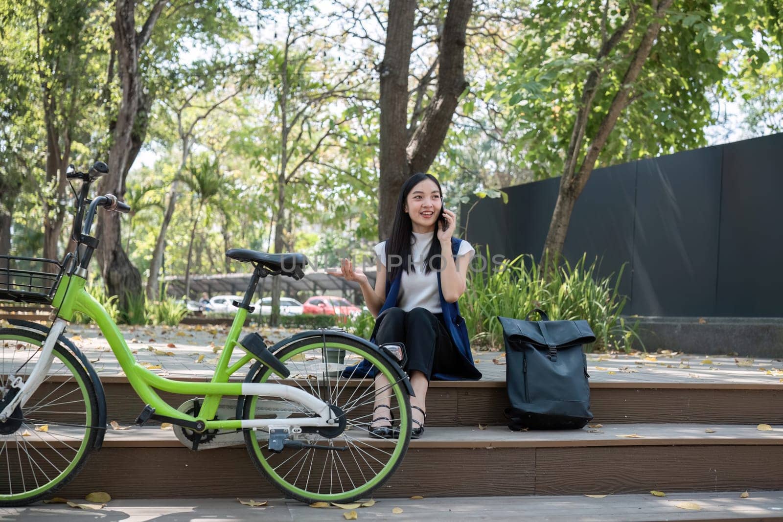 Asian business woman sitting and working in a nature park Travel by bicycle to save the environment.