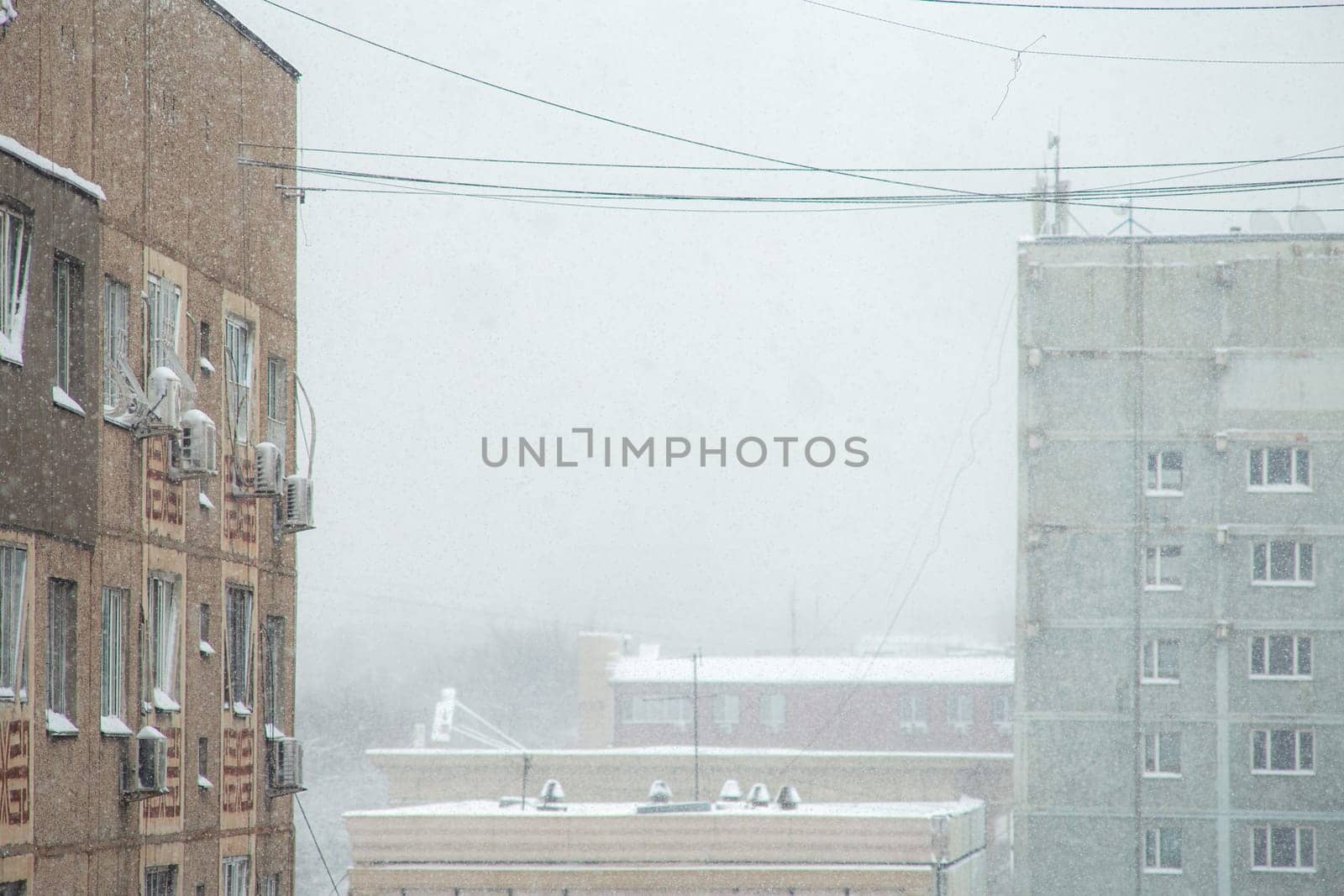 Tall apartment buildings covered with snow in a residential area of the city during a blizzard in the middle of winter