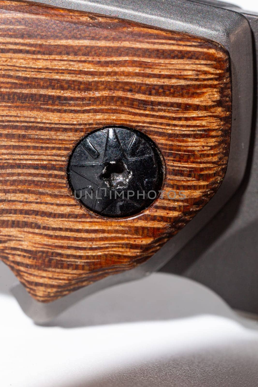 A black round screw with a textured surface is placed on a wooden background, showcasing its unique design.