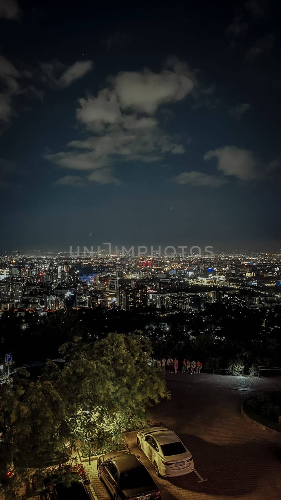 A beautiful view of a city at night from a mountaintop. The city is lit up by thousands of lights, and the sky is dark and clear.