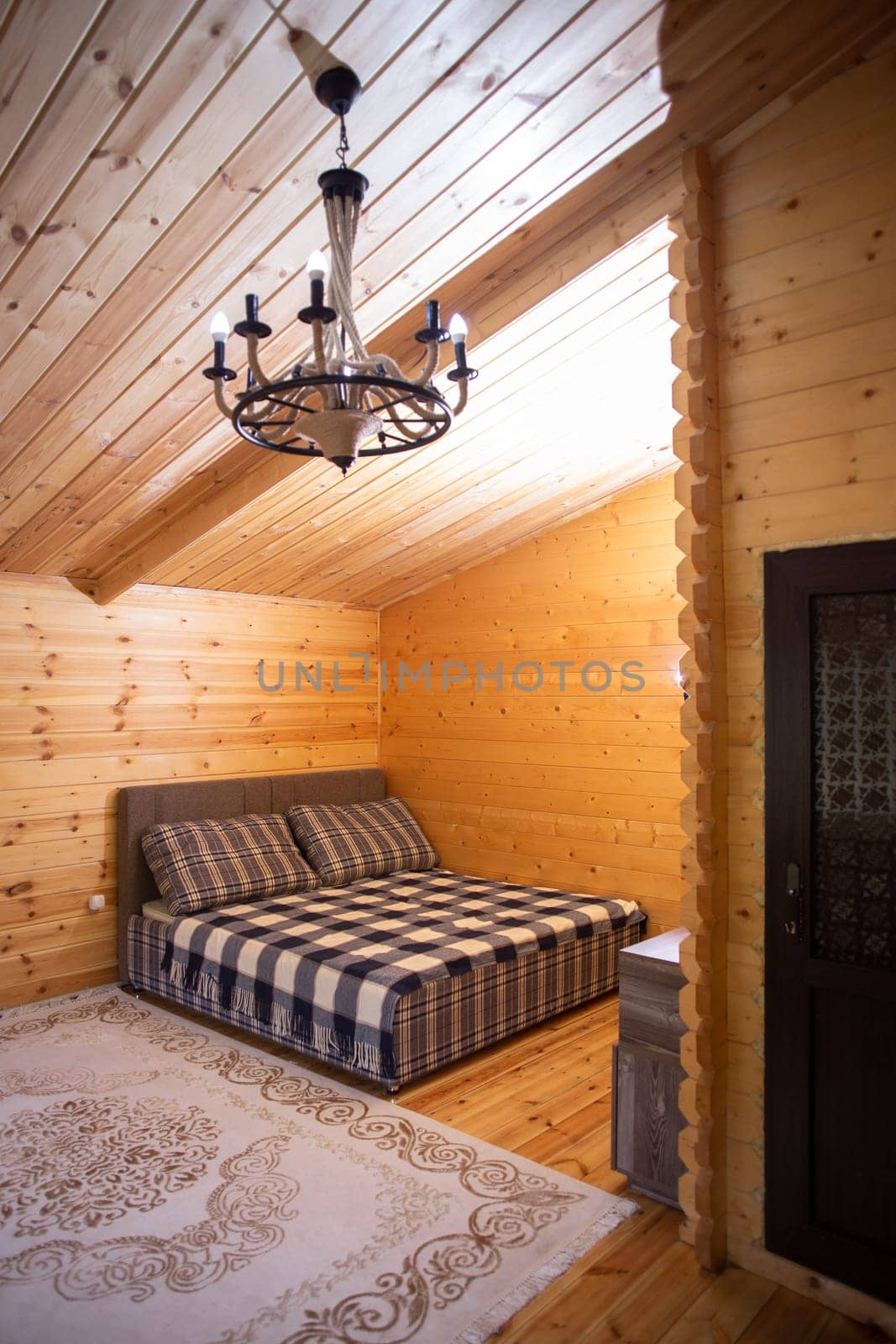 The bedroom is decorated with warm wood paneling and a soft, inviting bed. A beautiful chandelier provides soft lighting.