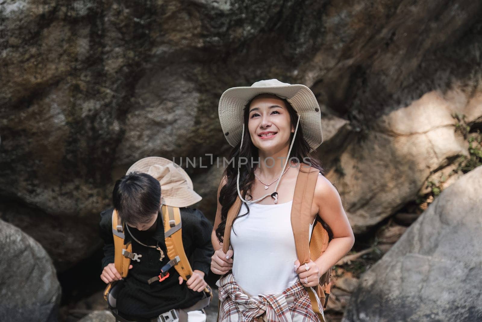 An Asian couple spent their vacation hiking along nature trail, visiting waterfall and enjoying forest views together. by wichayada
