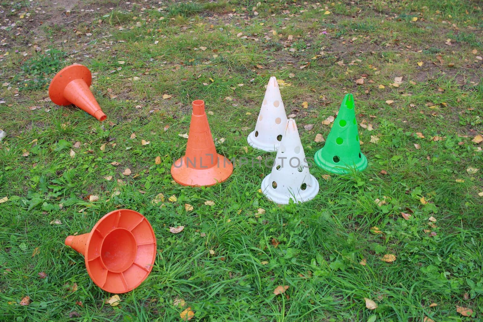 colorful plastic cones for sports games on the grass. by electrovenik