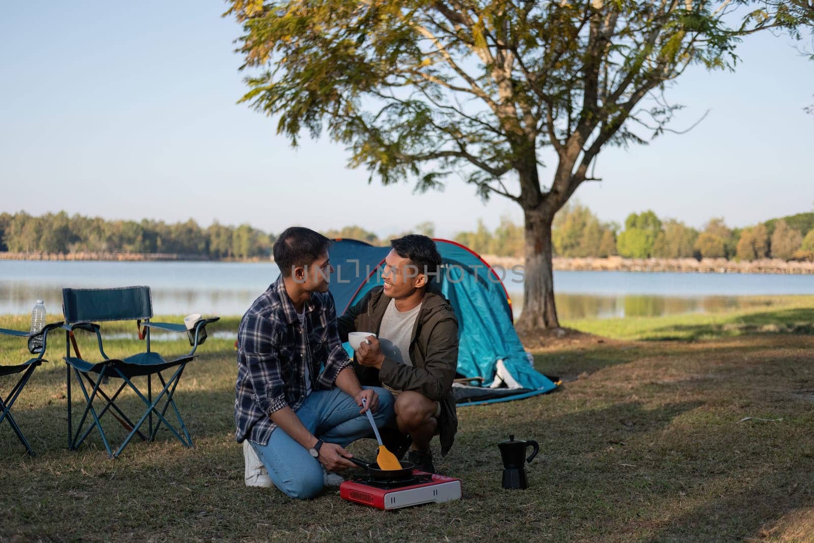 Happy Asian male gay couple on camping together in a forest. romantic vocation trip. lgbt concept by wichayada