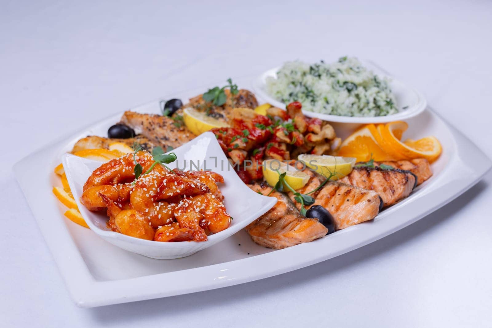 seafood mix on a white trellis. Delicious grilled fish, shrimp in sauce on the table by Pukhovskiy