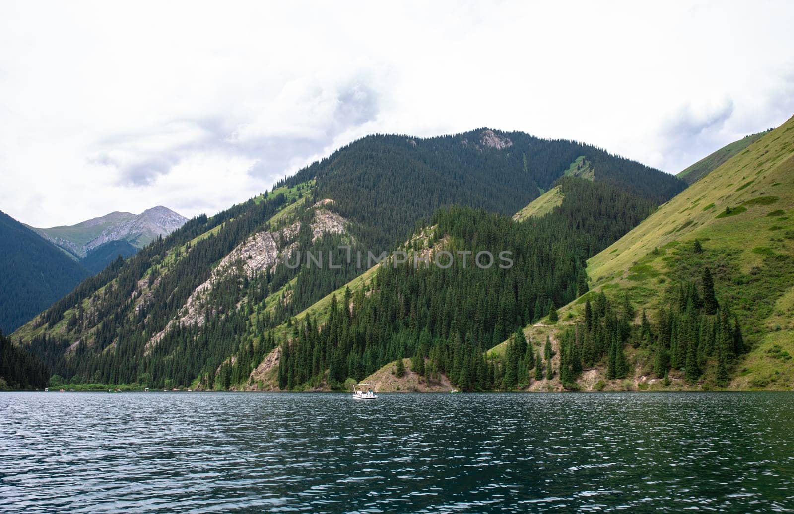 Picturesque mountain lake surrounded by dense green pine forest by Pukhovskiy