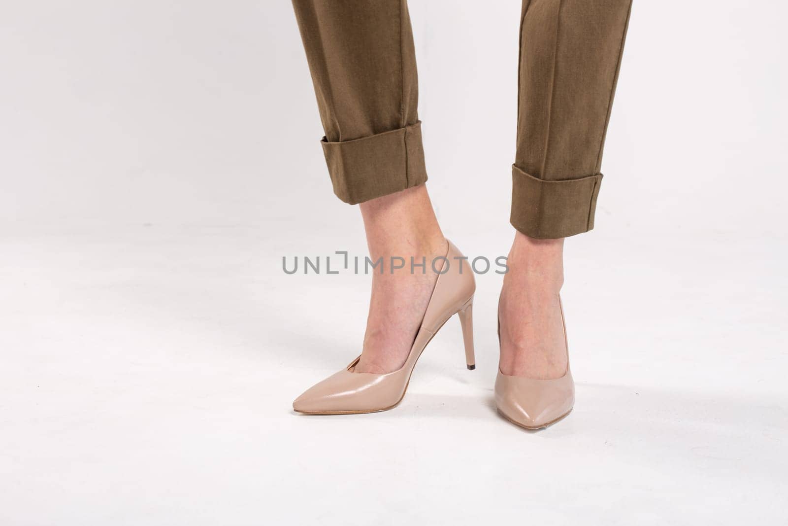 Fashion model posing in khaki pants and beige high heels. Isolated on a white background with copy space for text