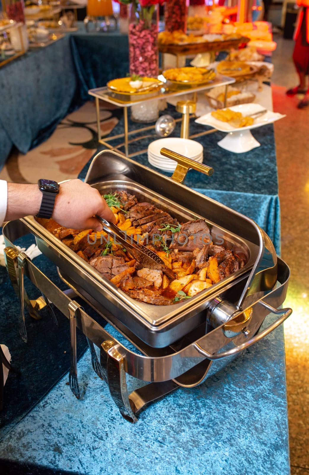 A buffet food warmer filled with delicious beef. The beef is cooked to perfection and is served with a variety of sauces and sides.