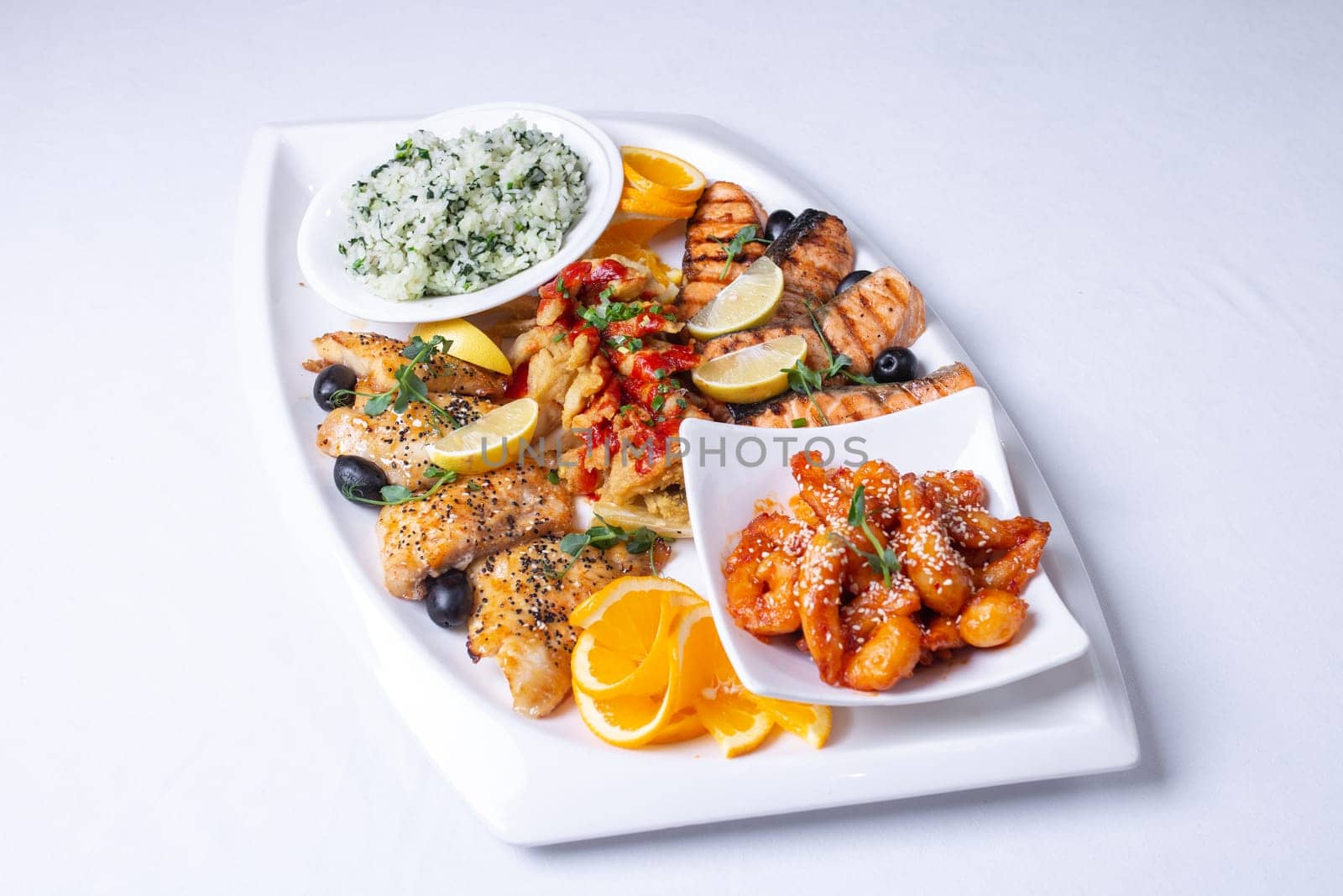 seafood mixture on a white grill. Delicious grilled fish, shrimp in sauce and salmon on the table.