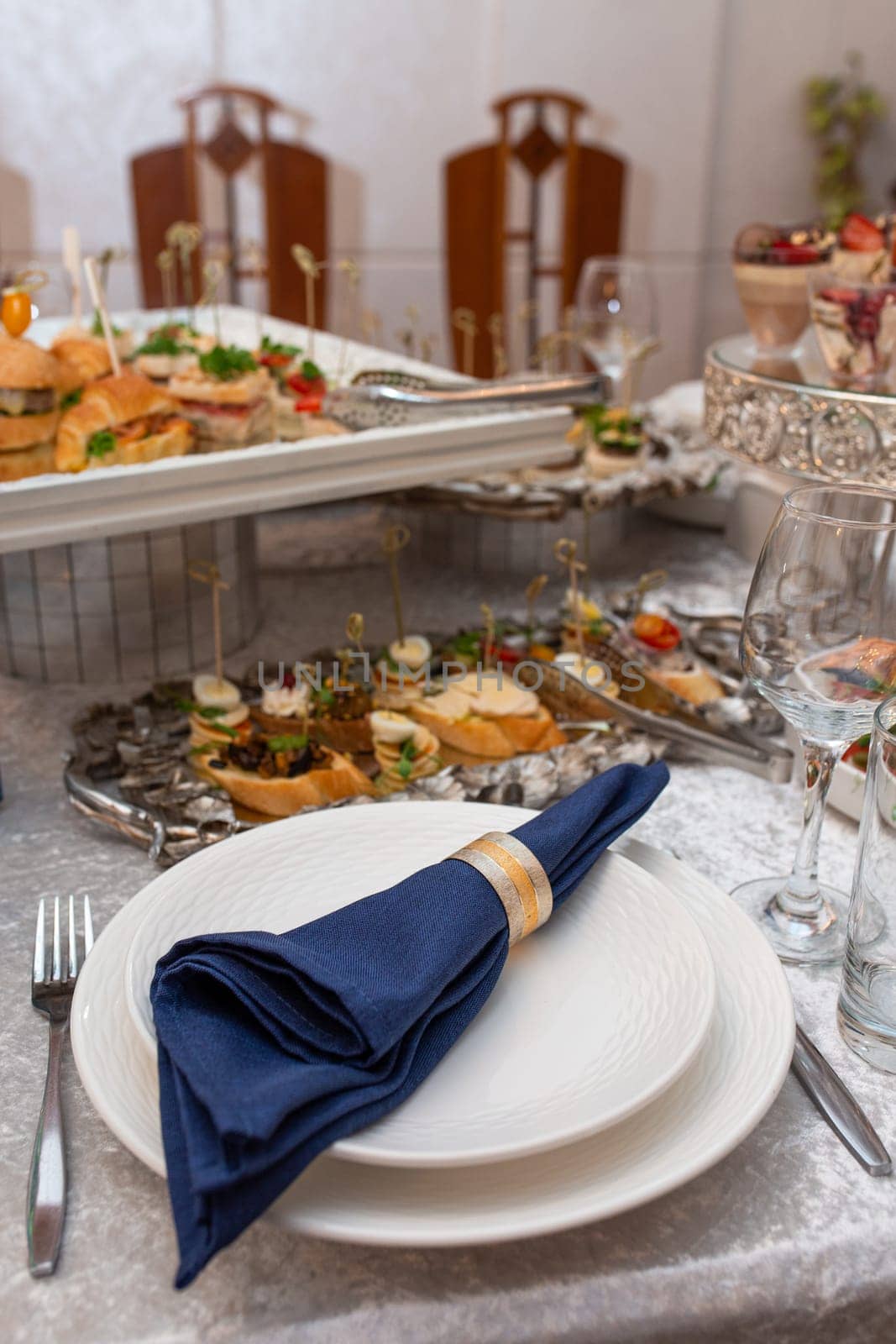 A beautifully set table with a blue napkin, silverware, and a glass of water. The table is decorated with flowers and candles.