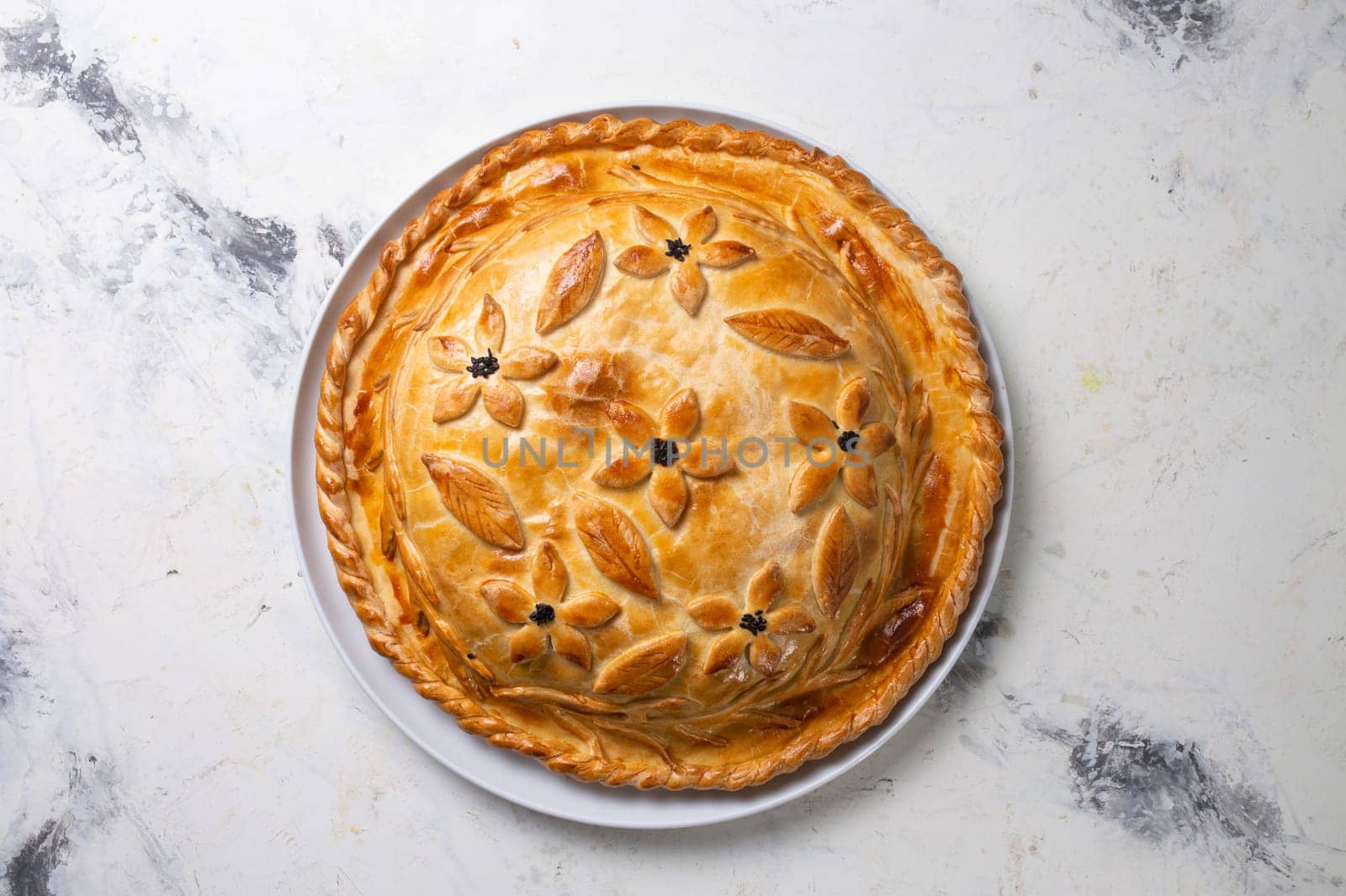 Rustic homemade round meat pie with golden crust, highlighted on a white background top view by Pukhovskiy