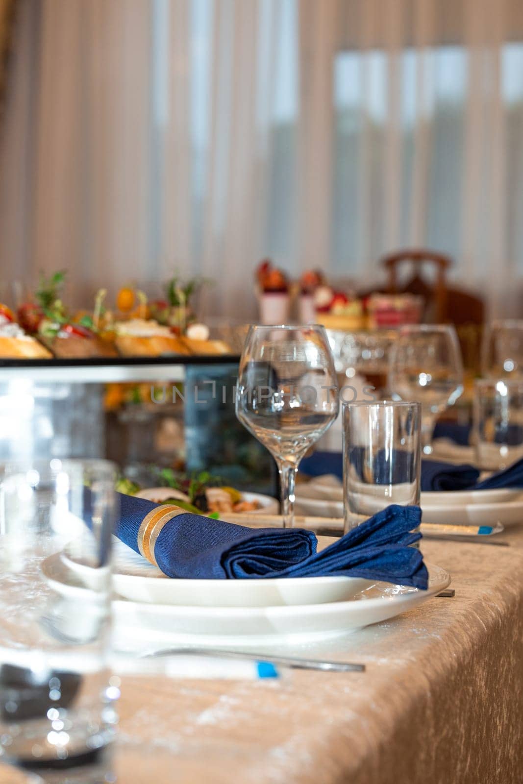 A beautifully set table with a blue napkin, silverware, and a glass of water. The table is decorated with flowers and candles.