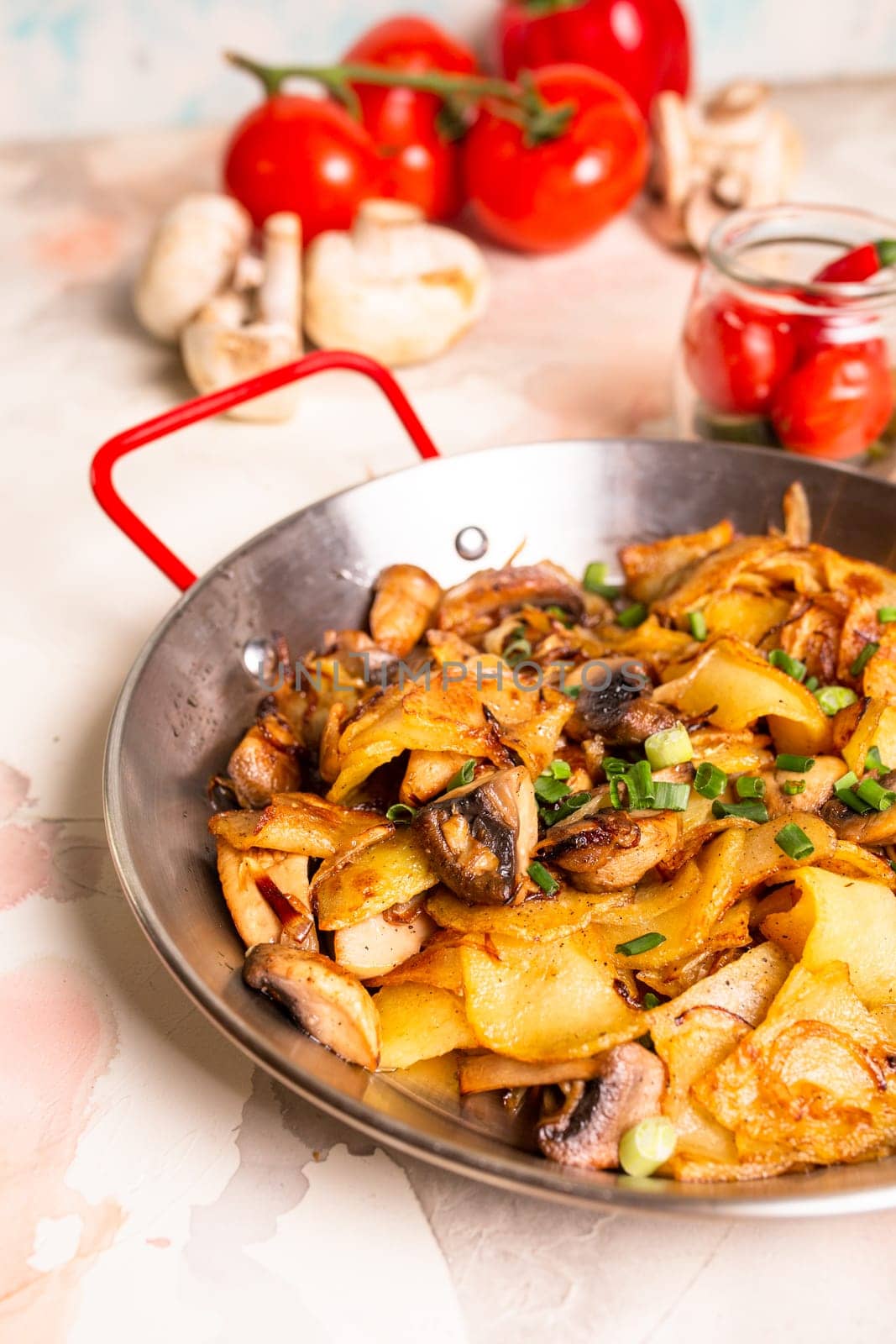 Sliced potatoes, fresh mushrooms, and diced onions sizzling in a frying pan on a clean white background, ready to be cooked.