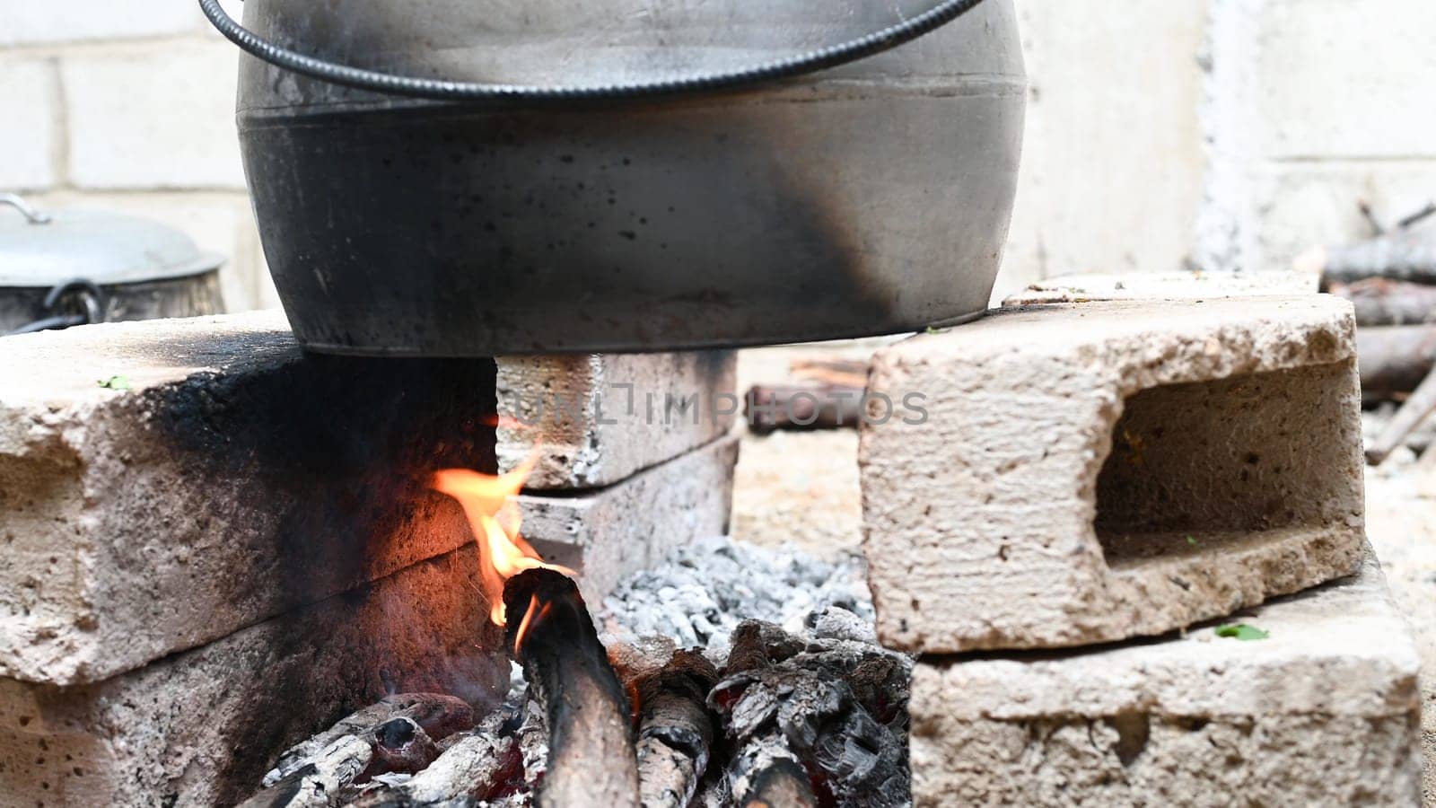 Holiday food fire cooking pot firewood. Preparing food on fire. Cast iron pot fire wood burning in stone oven cooking background. by Peruphotoart