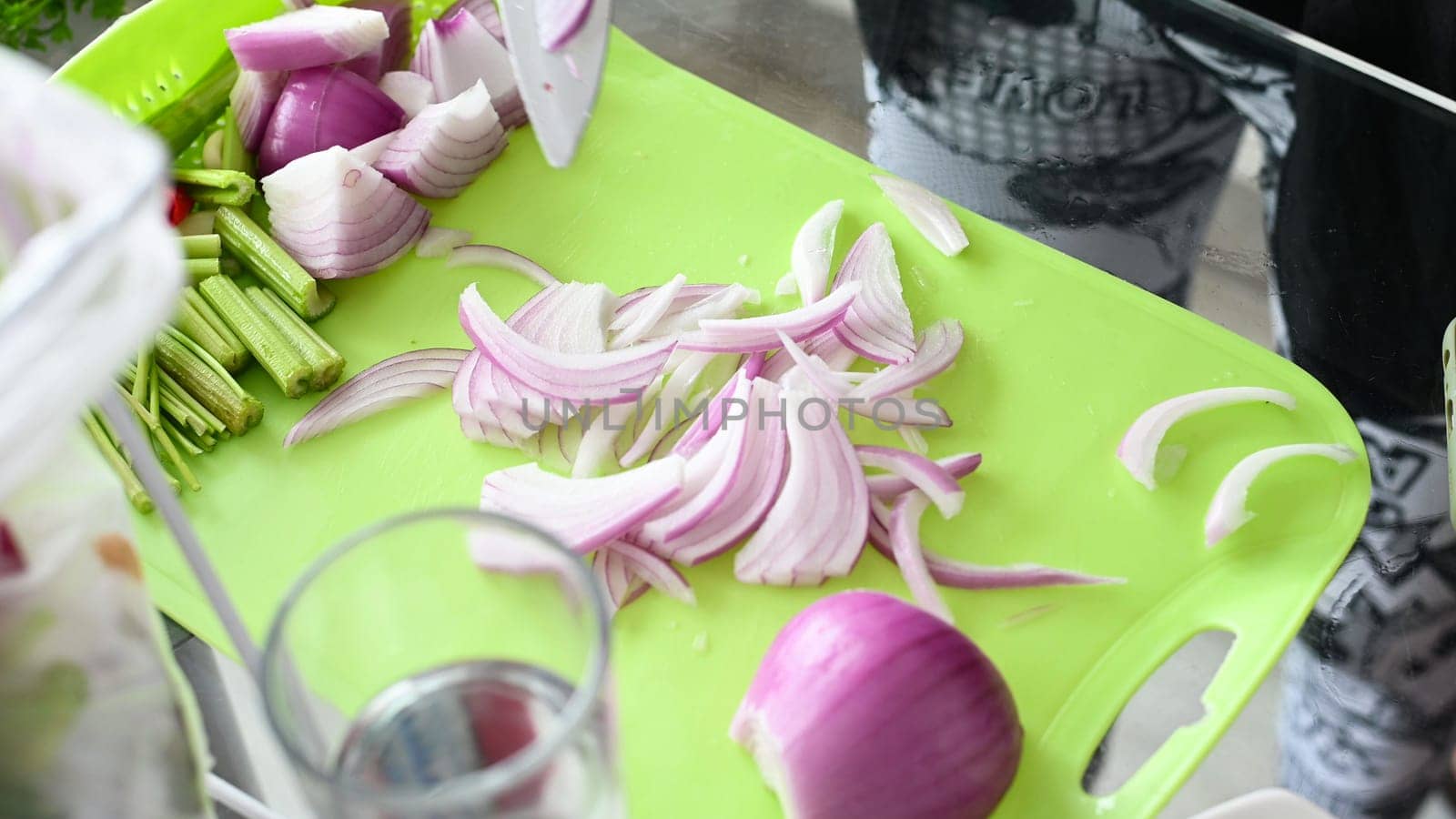 Chopping onion, close-up. Red onions close up. Female hands cut onions in the kitchen. The woman cuts onions on a yellow plastic board. by Peruphotoart