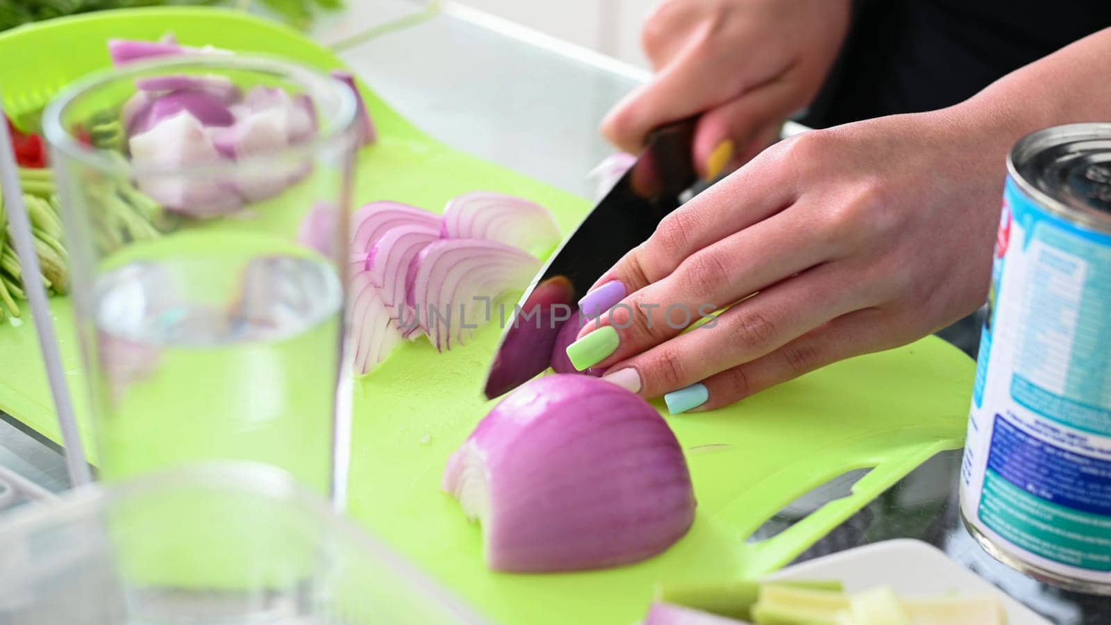 Chopping onion, close-up. Red onions close up. Female hands cut onions in the kitchen. The woman cuts onions on a yellow plastic board