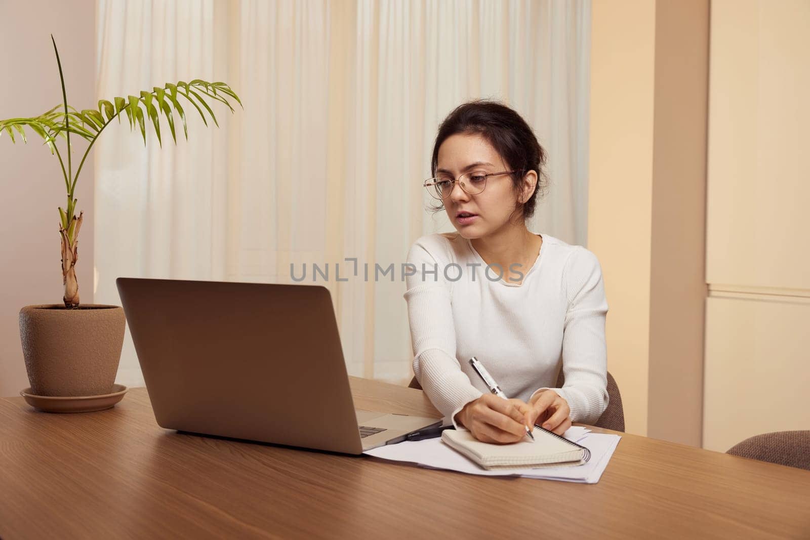 pretty woman in glasses using laptop and communicates with customer on internet at home