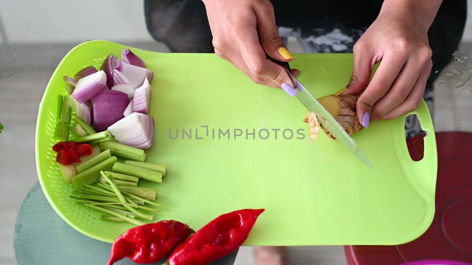 Chopping ginger, close-up. Red onions close up. Female hands cut ginger in the kitchen. The woman cuts gingers on a yellow plastic board