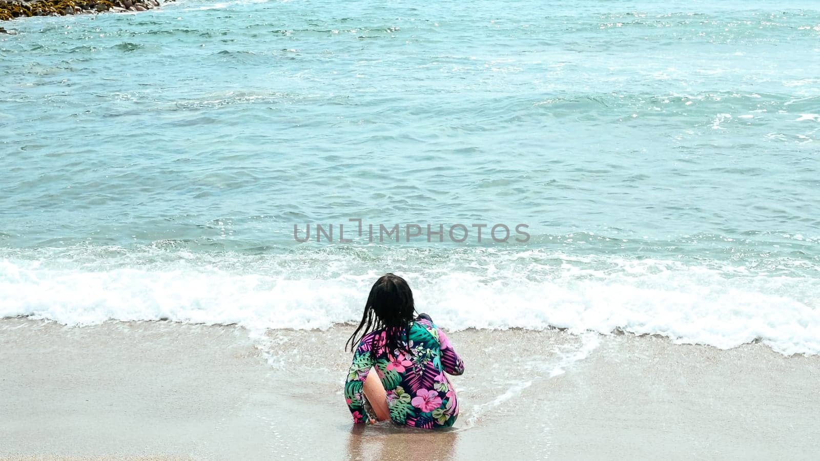Happy girl sitting on the water's edge in the beautiful beach of San Bartolo south of Lima - Peru. Summer Vacation