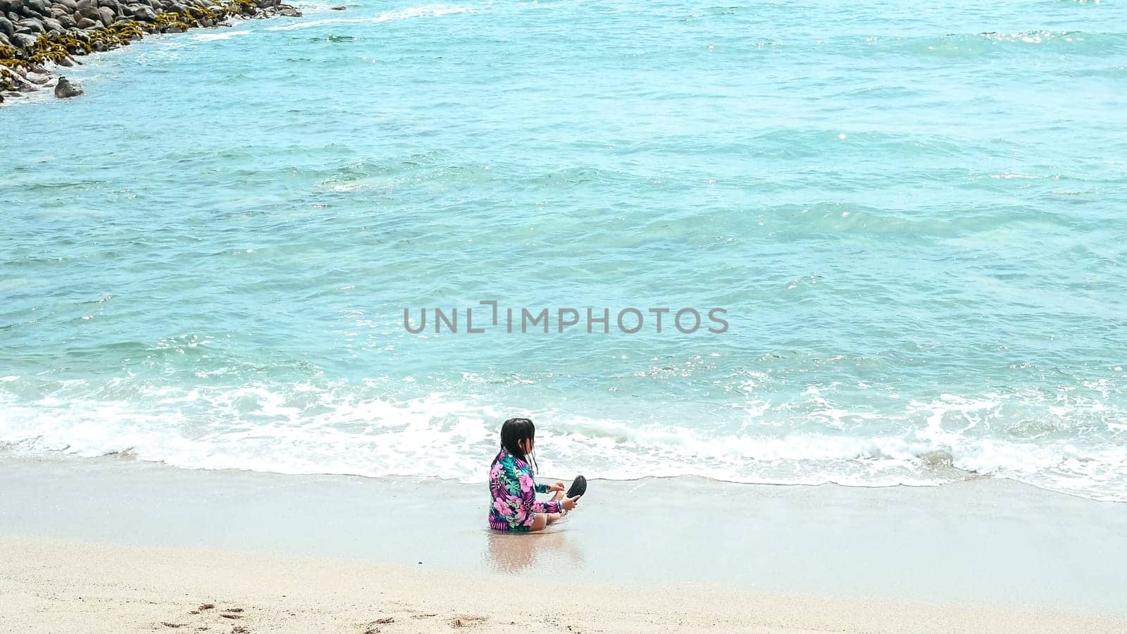 Happy girl sitting on the water's edge in the beautiful beach of San Bartolo south of Lima - Peru. Summer Vacation. by Peruphotoart