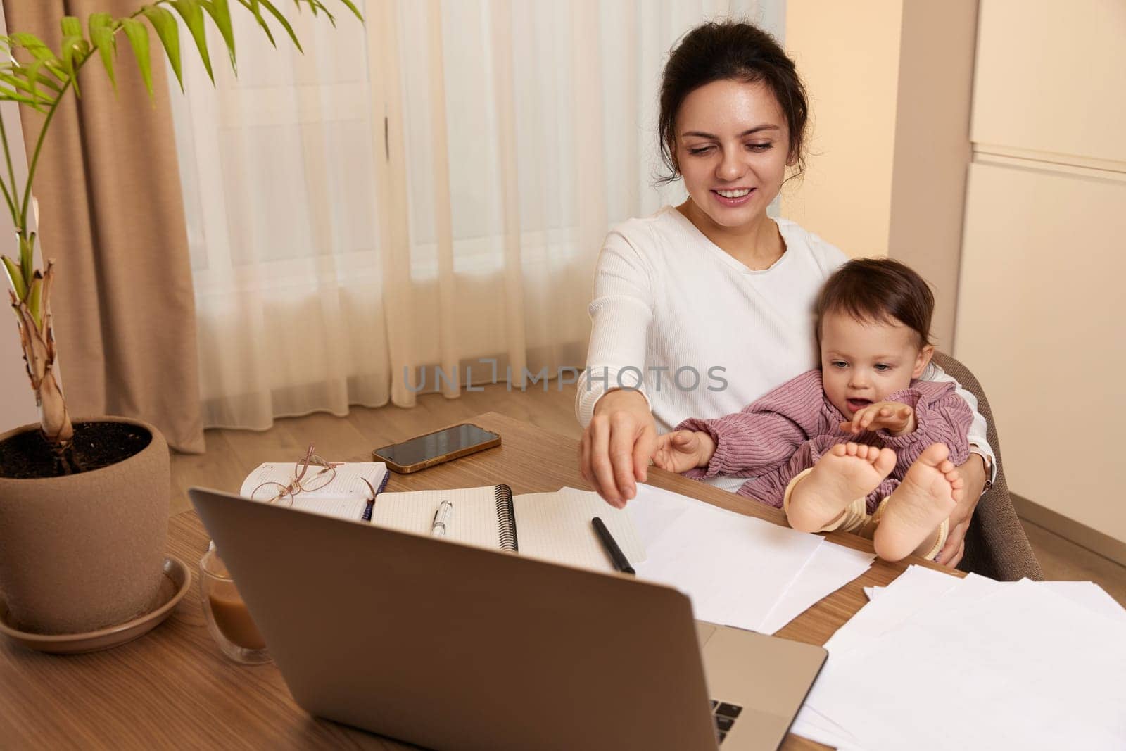 happy woman working and and playing with her baby girl at home