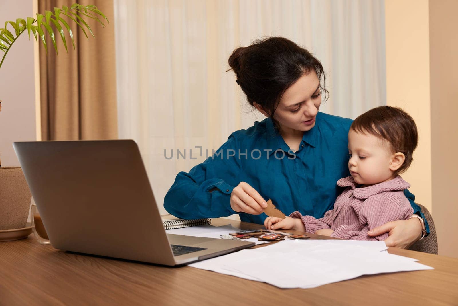 beautiful businesswoman working on laptop with her little child girl at home