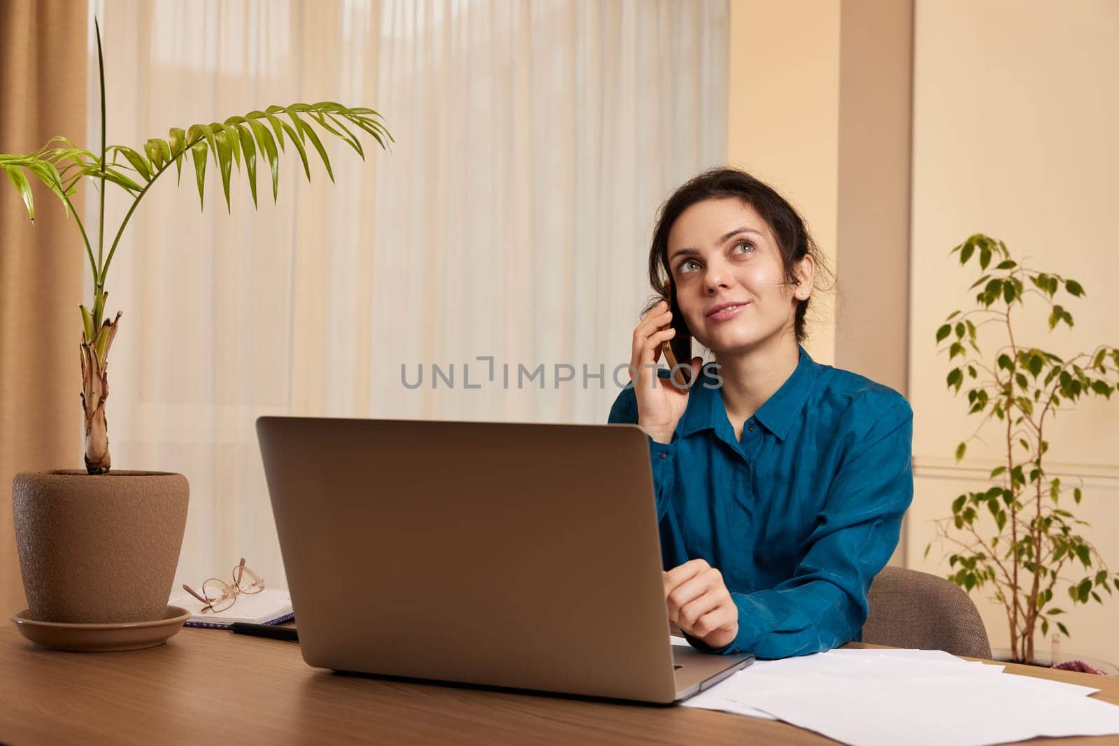 beautiful businesswoman working on laptop and communicates with customer by phone at home