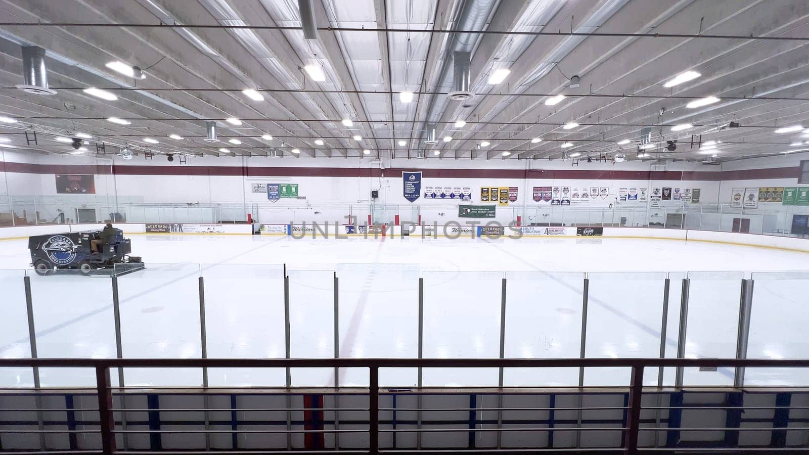 Denver, Colorado, USA-February 17, 2024-ice resurfacer moves across the surface of an empty hockey rink, surrounded by banners and seating, preparing the ice for athletes and skaters.