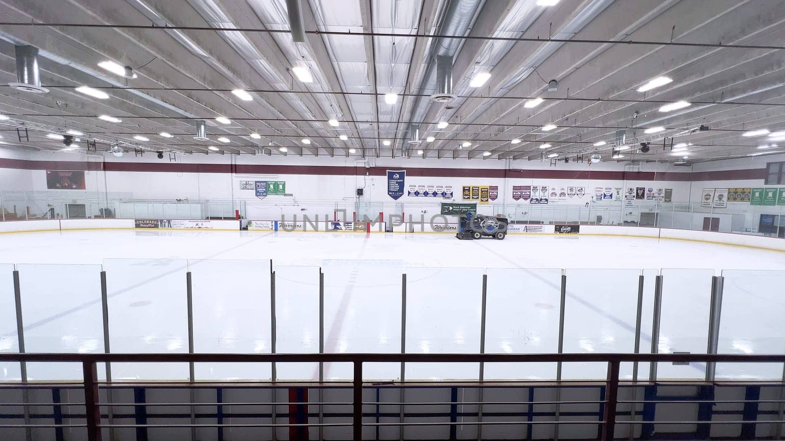 Denver, Colorado, USA-February 17, 2024-ice resurfacer moves across the surface of an empty hockey rink, surrounded by banners and seating, preparing the ice for athletes and skaters.