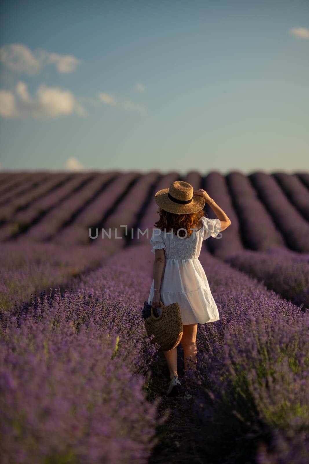 Back view woman lavender sunset. Happy woman in white dress holds lavender bouquet. Aromatherapy concept, lavender oil, photo session in lavender by Matiunina