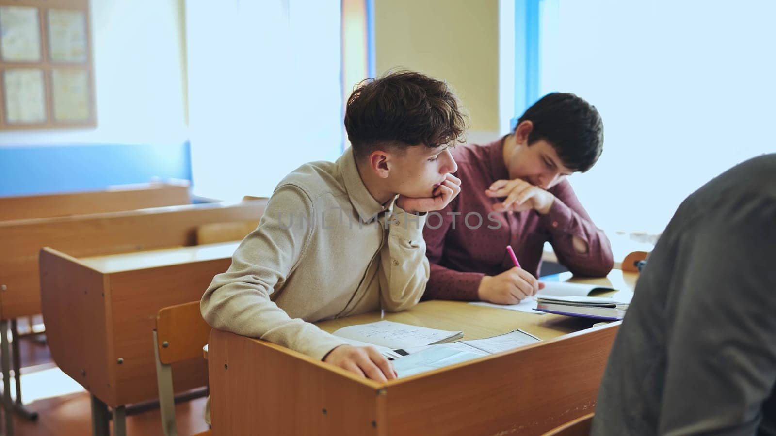 Schoolboys at a desk during class. by DovidPro