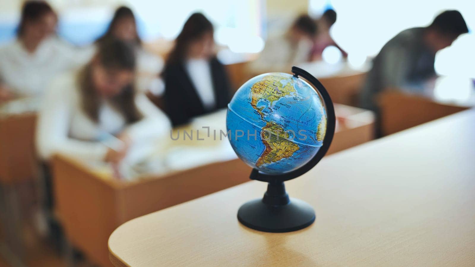 A globe of the world with textbooks in the background of a lesson in a school classroom. The globe shows North and South America