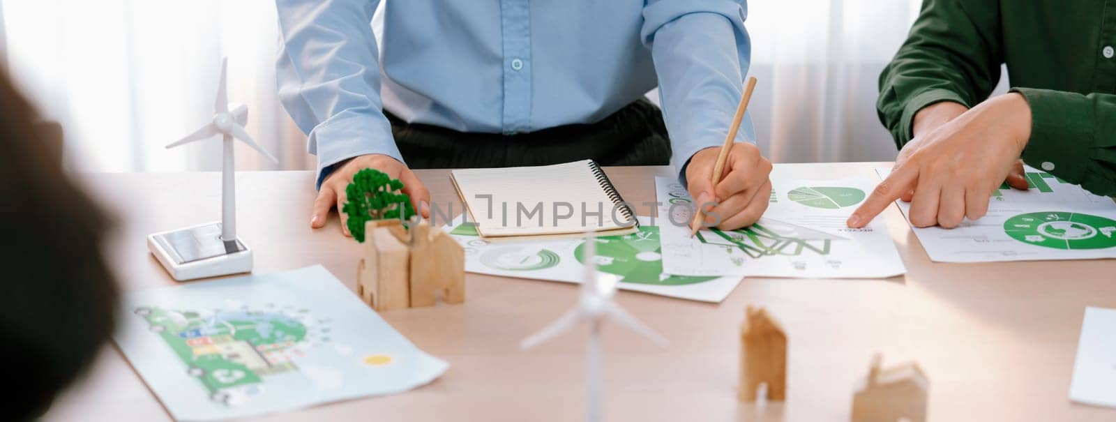 Business people invest in green business plan at meeting room on table with house model and wind mill placed represented eco house and renewable energy. Closeup. Delineation.