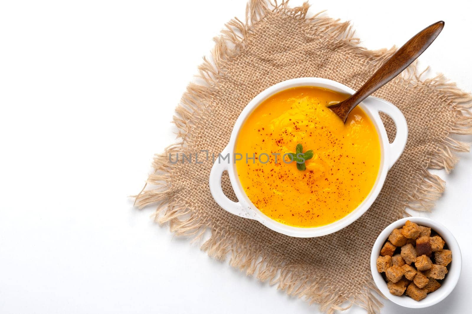 Pumpkin soup with croutons on white background, with copy space for text.