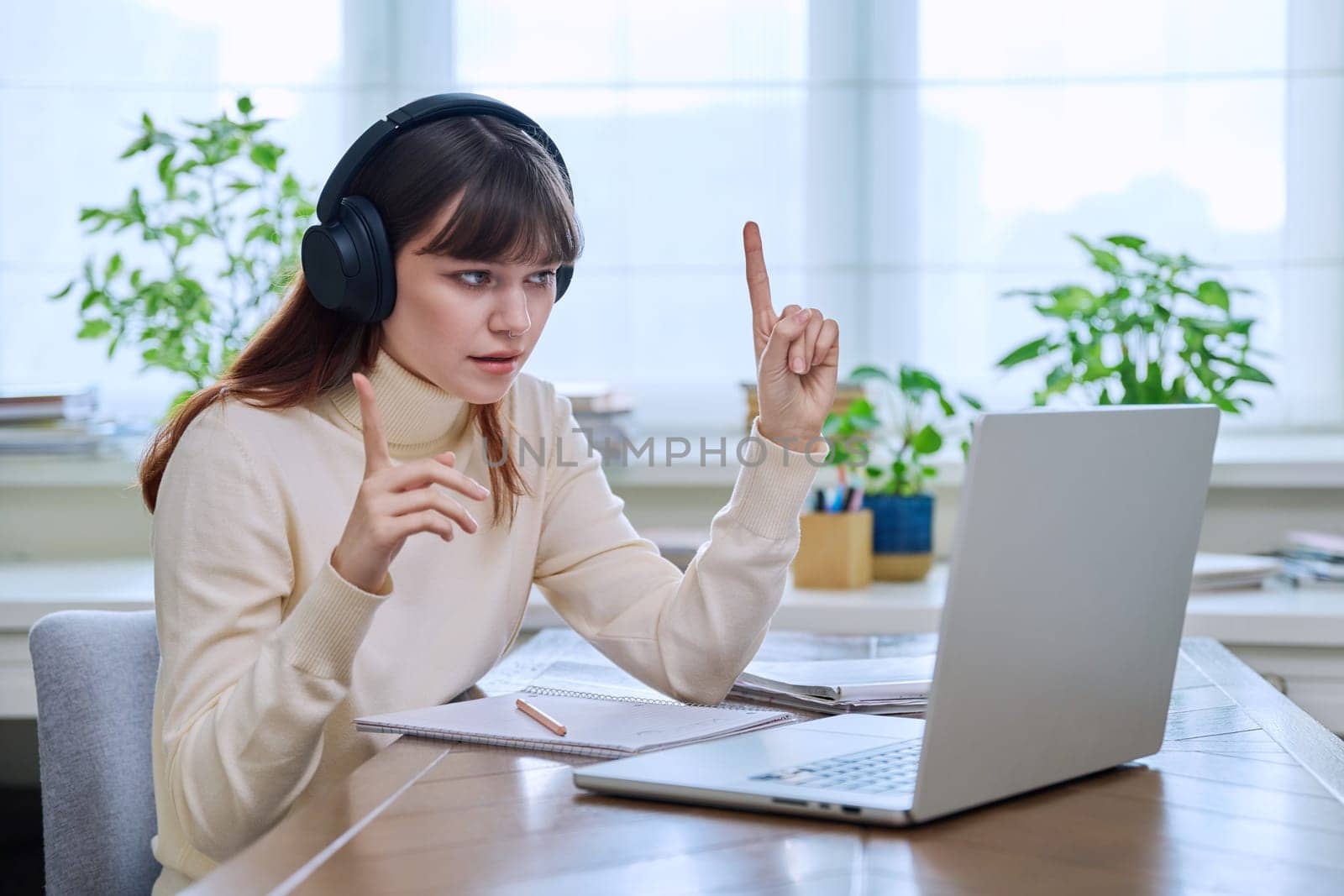 Teenage girl college student in headphones having video conference chat online meeting lesson webinar on computer laptop screen, sitting at desk at home. E-learning, education, technology, knowledge