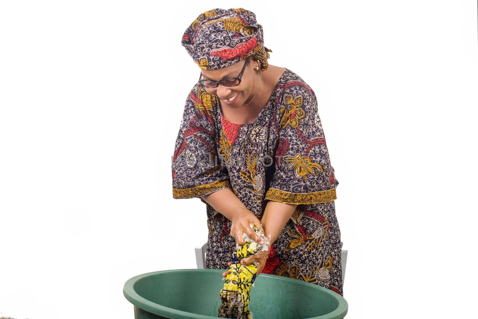 African woman standing above the laundry bowl washing clothes isolated on white background.
