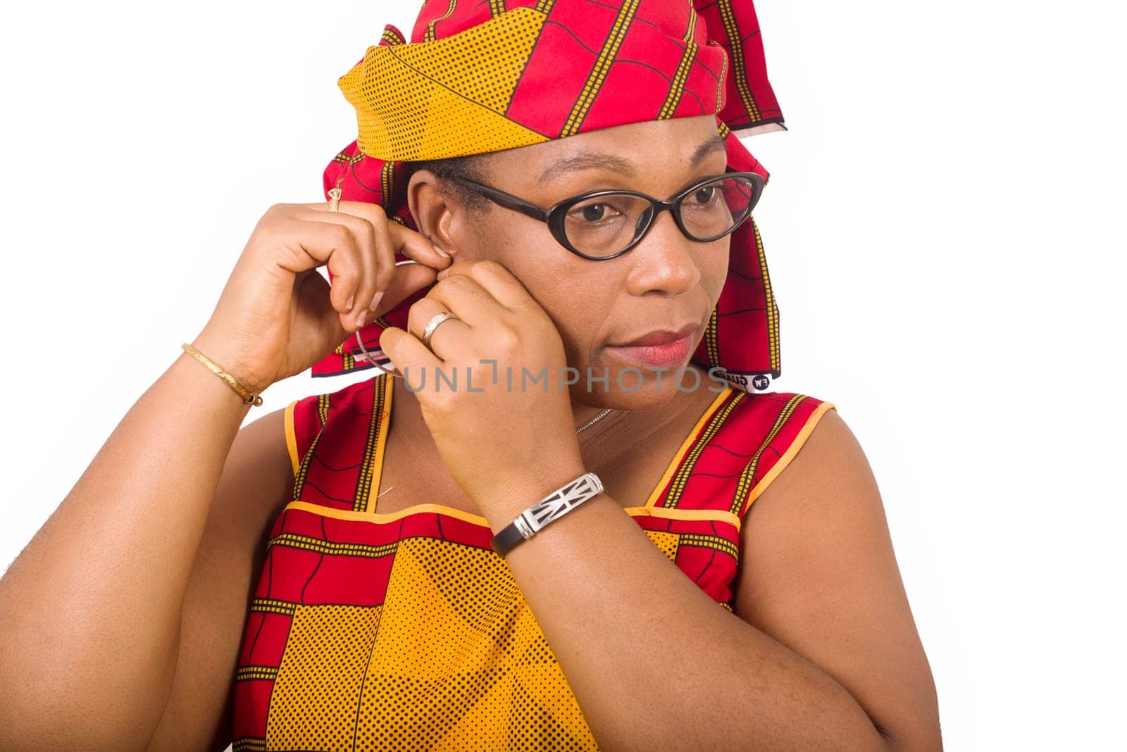 charming woman. african woman in red loincloth with head scarf putting earring on white background