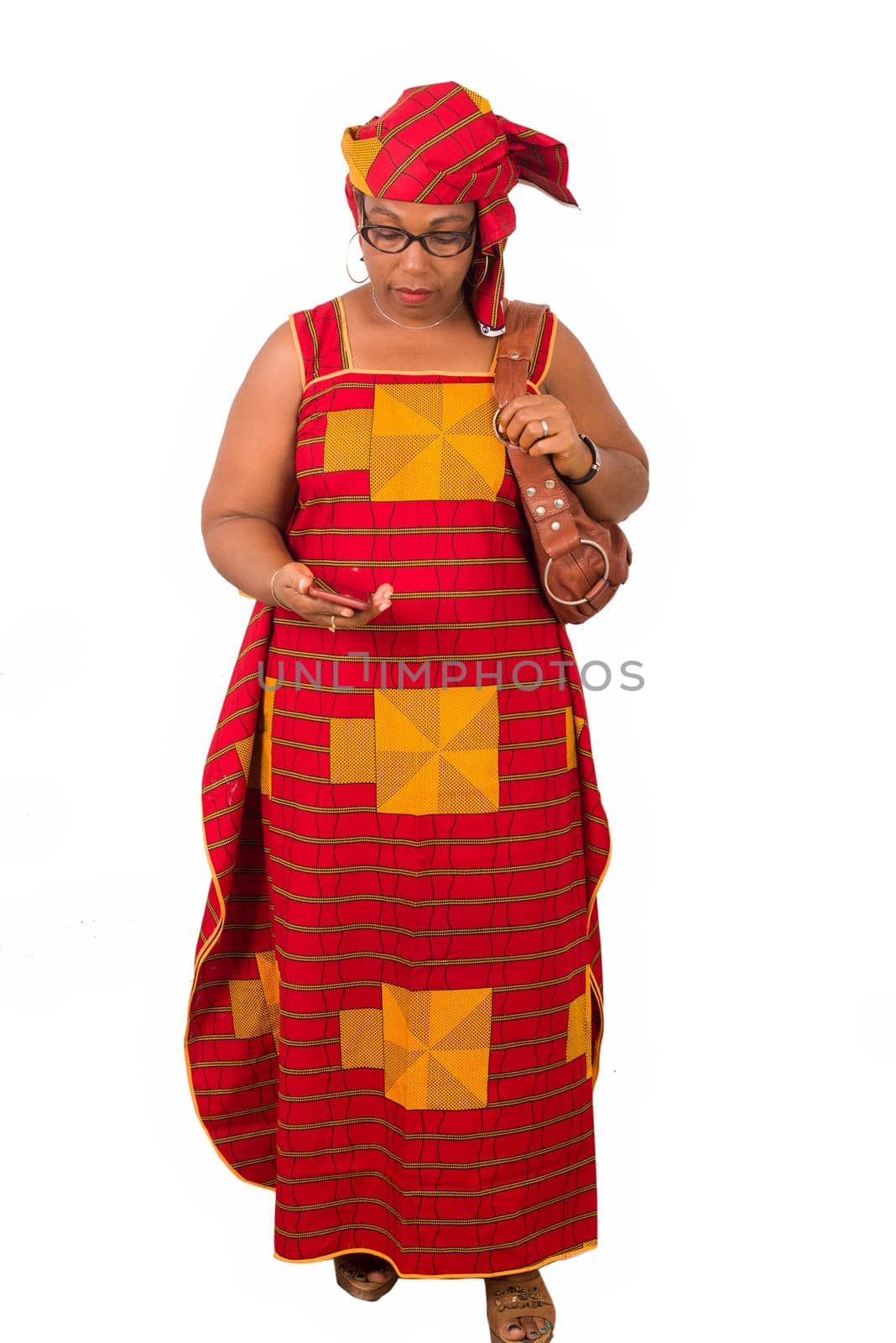 african woman in red clothes and holding purse, sends or reads message on cellphone while walking isolated on white background