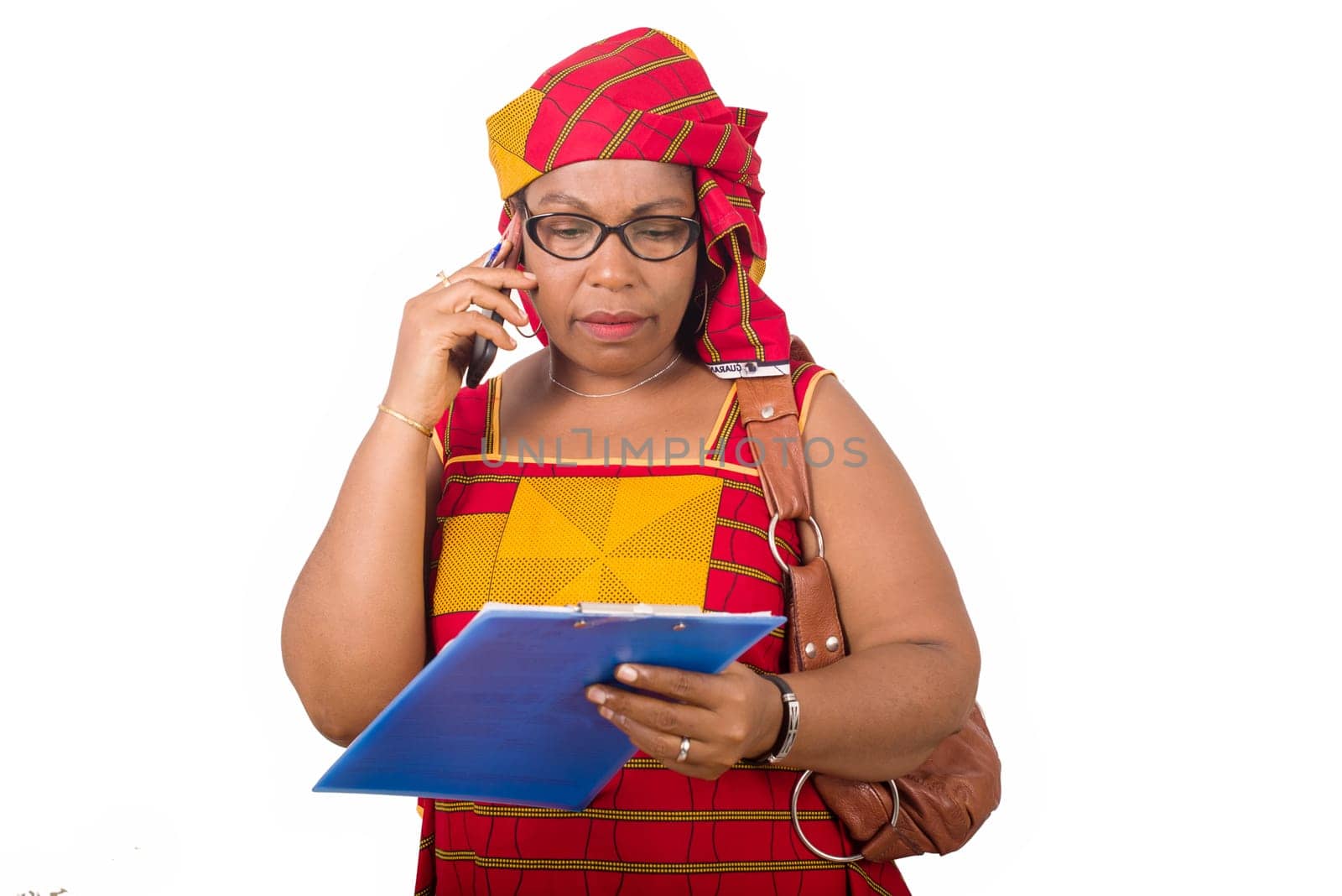 mature businesswoman standing on white background communicating on cellphone looking at notebook.