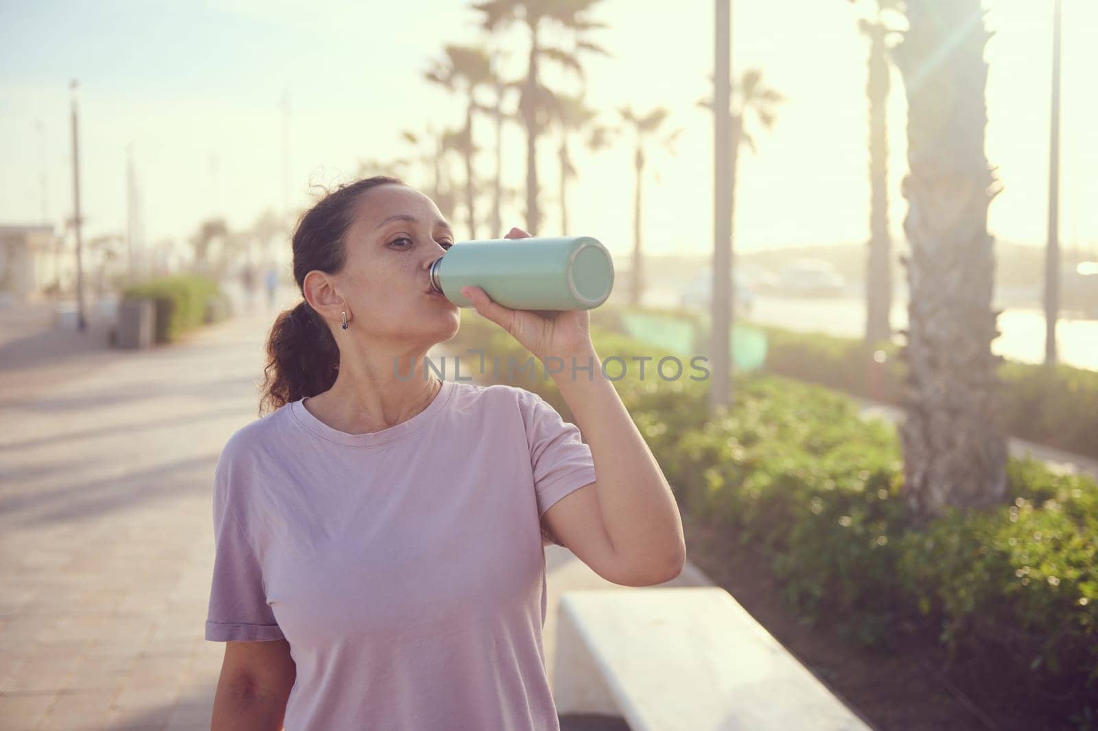 Wellness and health. Young female athlete, sportswoman with bottle of fresh clear water after sports workout outdoors by artgf