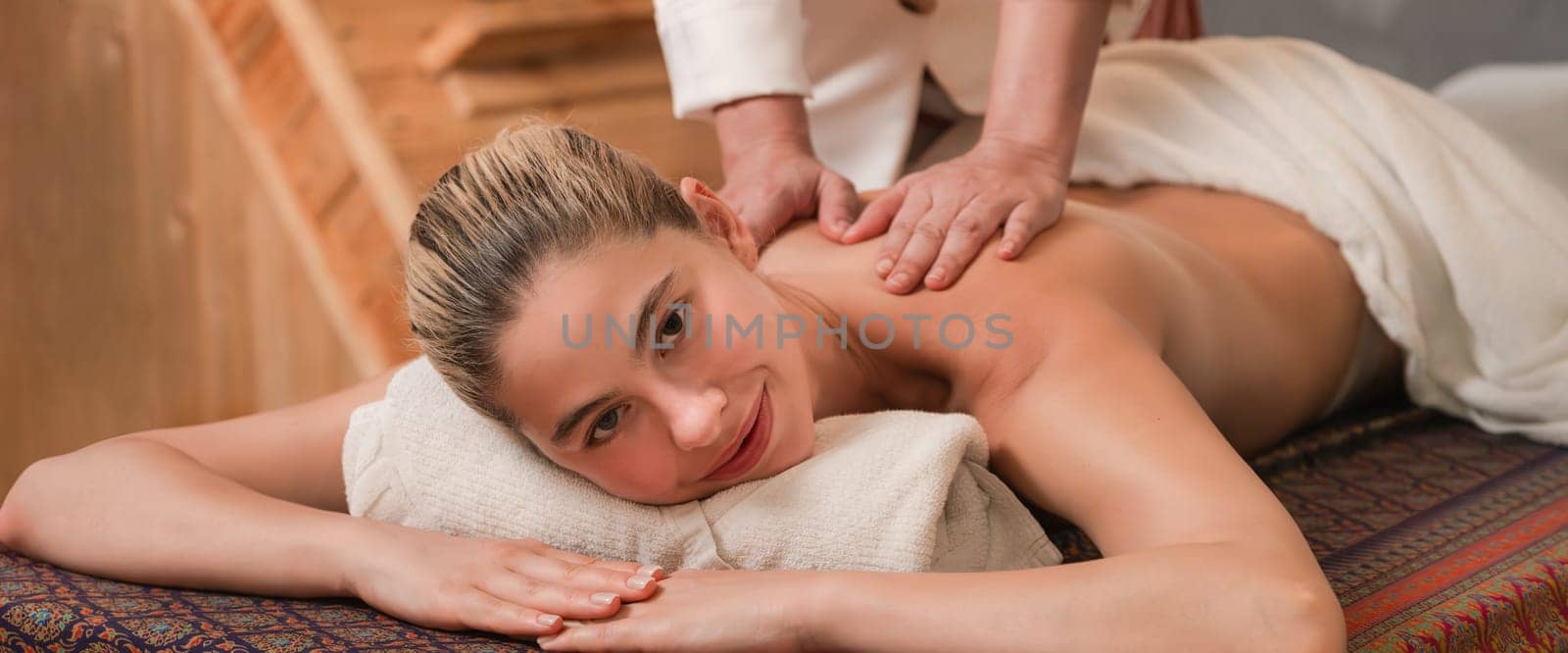 A pretty girl having a massage while looking at camera at sauna. Tranquility. by biancoblue