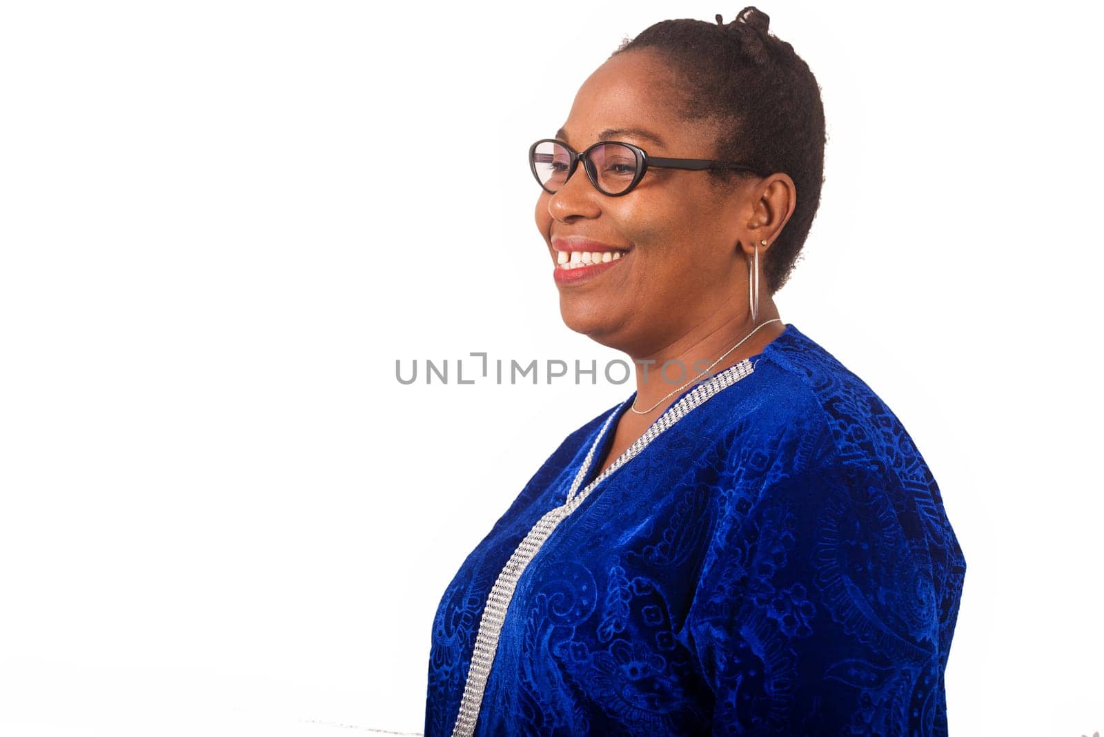 mature woman standing on white background looking to profile in smiling.