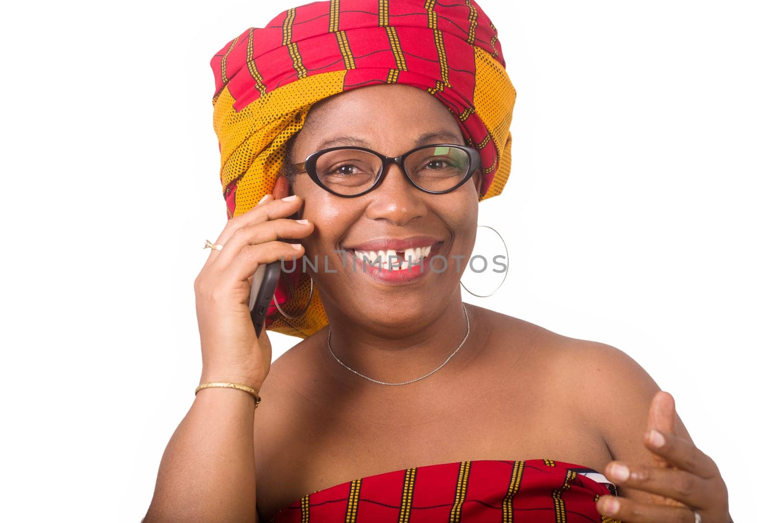 mature woman in glasses standing on white background communicating on cell phone laughing.